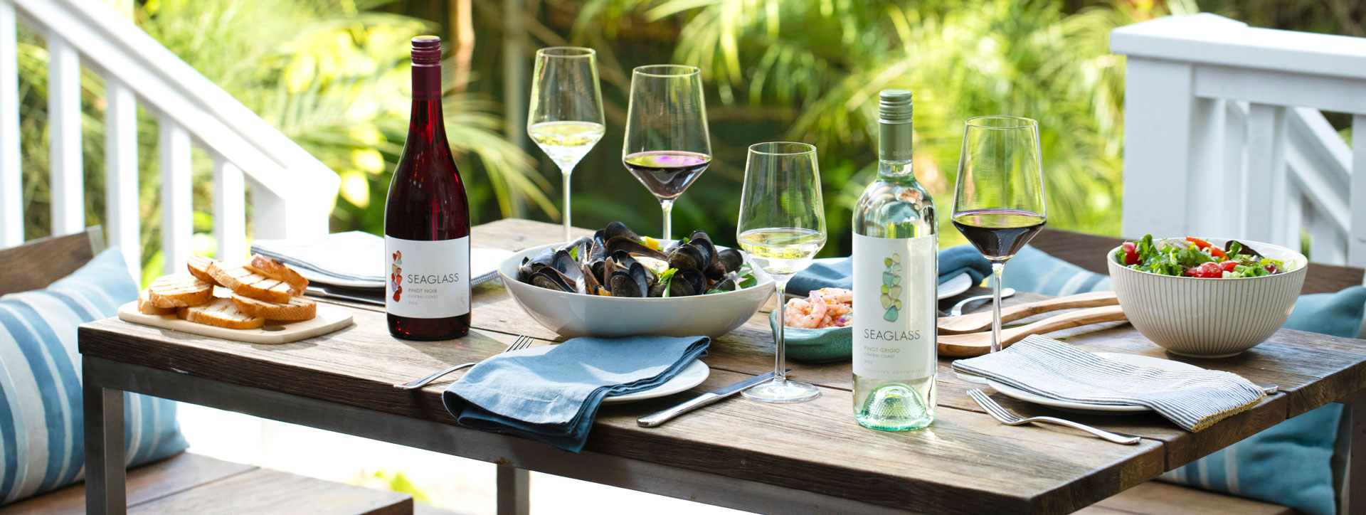 Bottles of Seaglass Pinot Noir red wine and Pinot Grigio white wine, on a beautifully laid outdoor dinner table
