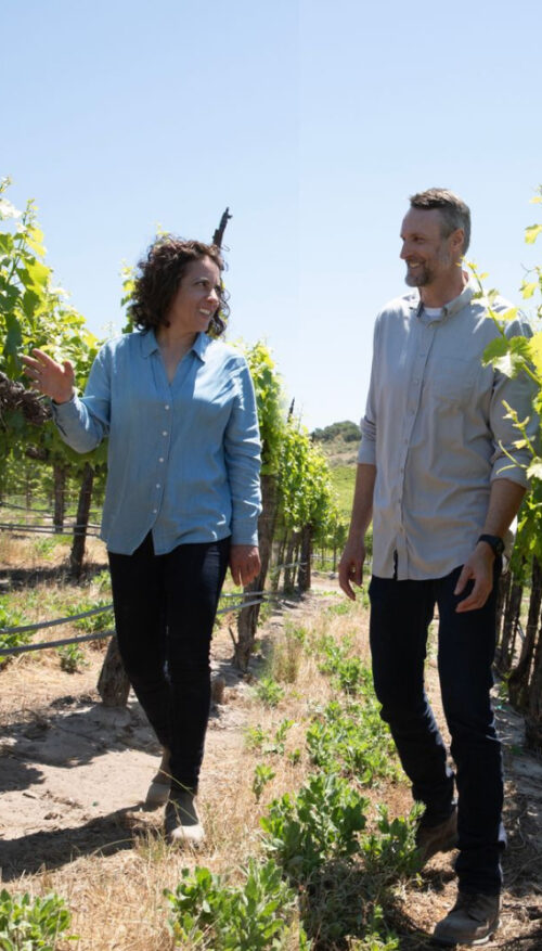 Winemaker Christine Morrison and viticulturist Matt Frank chat while walking through a sunny vineyard together