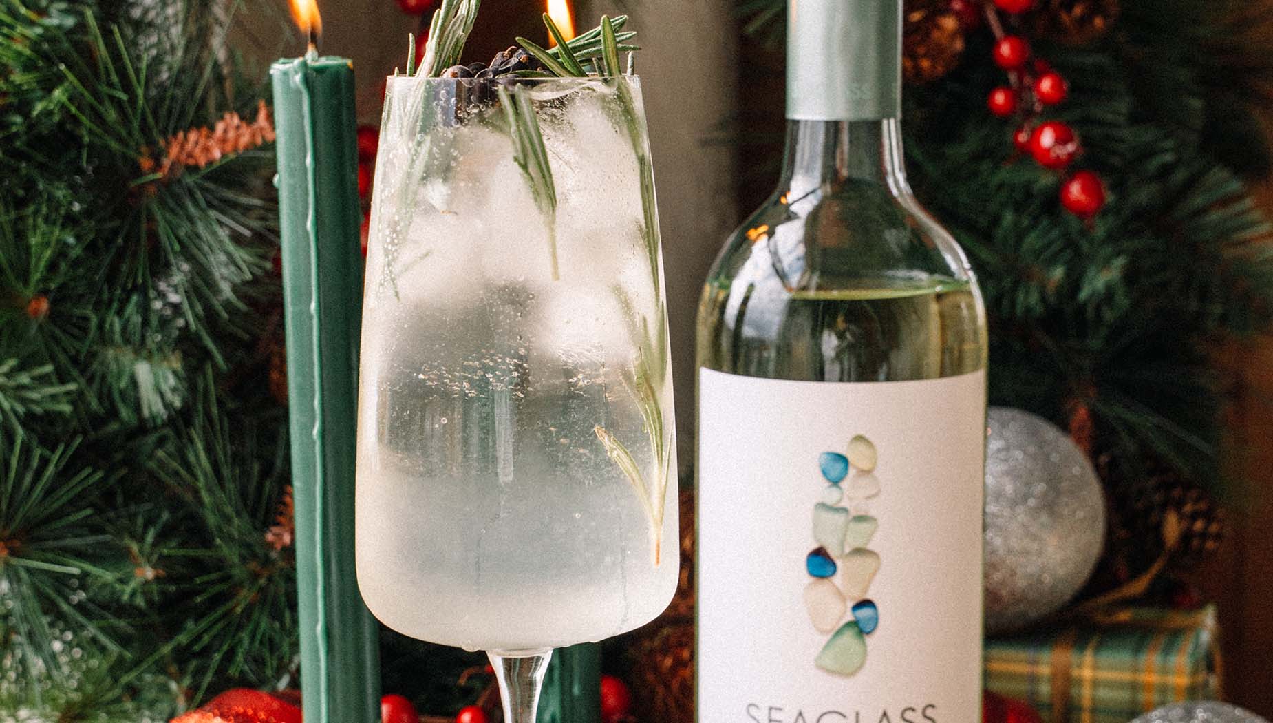 Color image of a bottle of SEAGLASS Sauvignon Blanc next to a clear cocktail with holiday garnishes