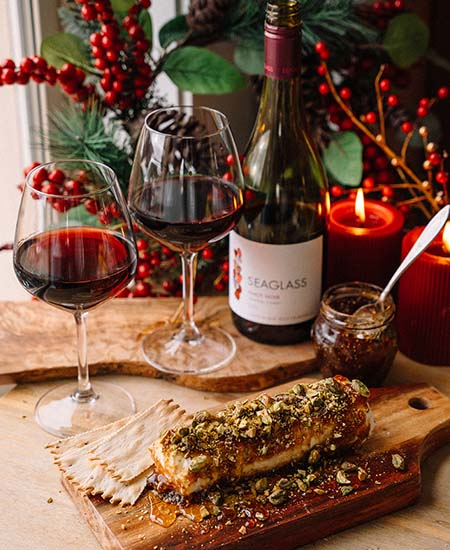A bottle of SEAGLASS Pinot Noir behind a nutty fig log on a tray