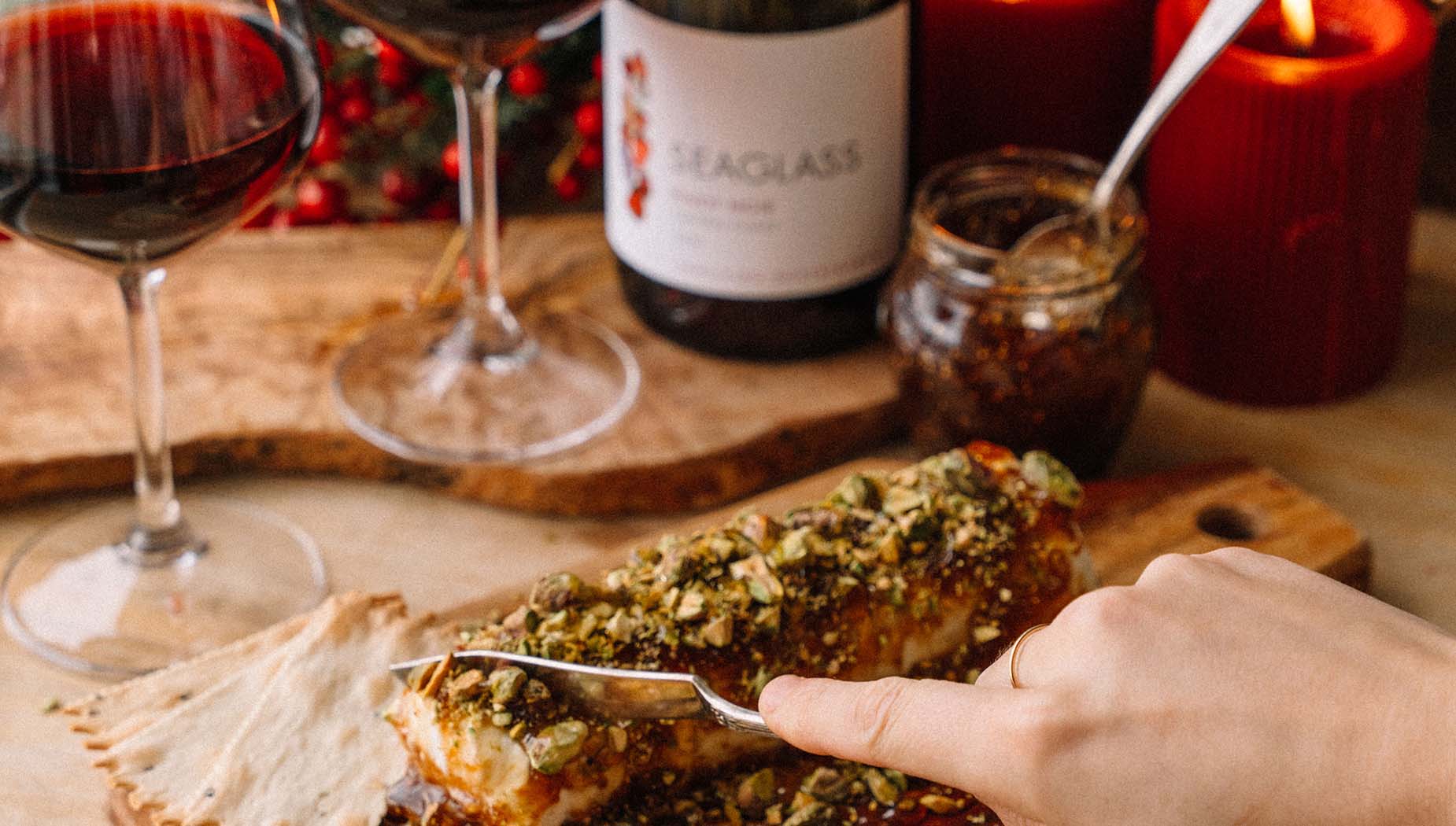 A bottle of SEAGLASS Pinot Noir behind a nutty fig log on a tray